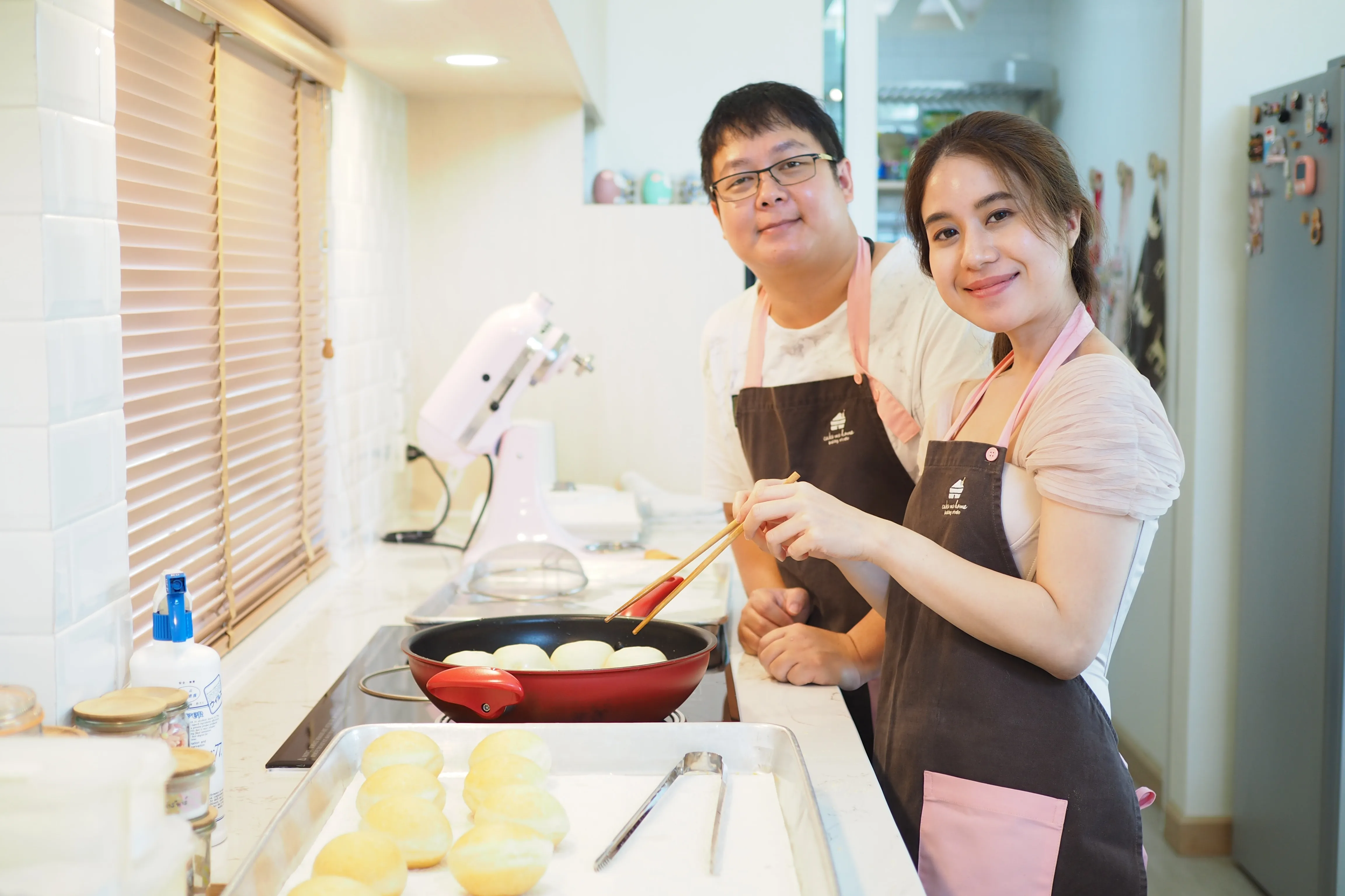 คู่เรียนกำลังทอดแป้งโดนัทในครัวสตูดิโอ