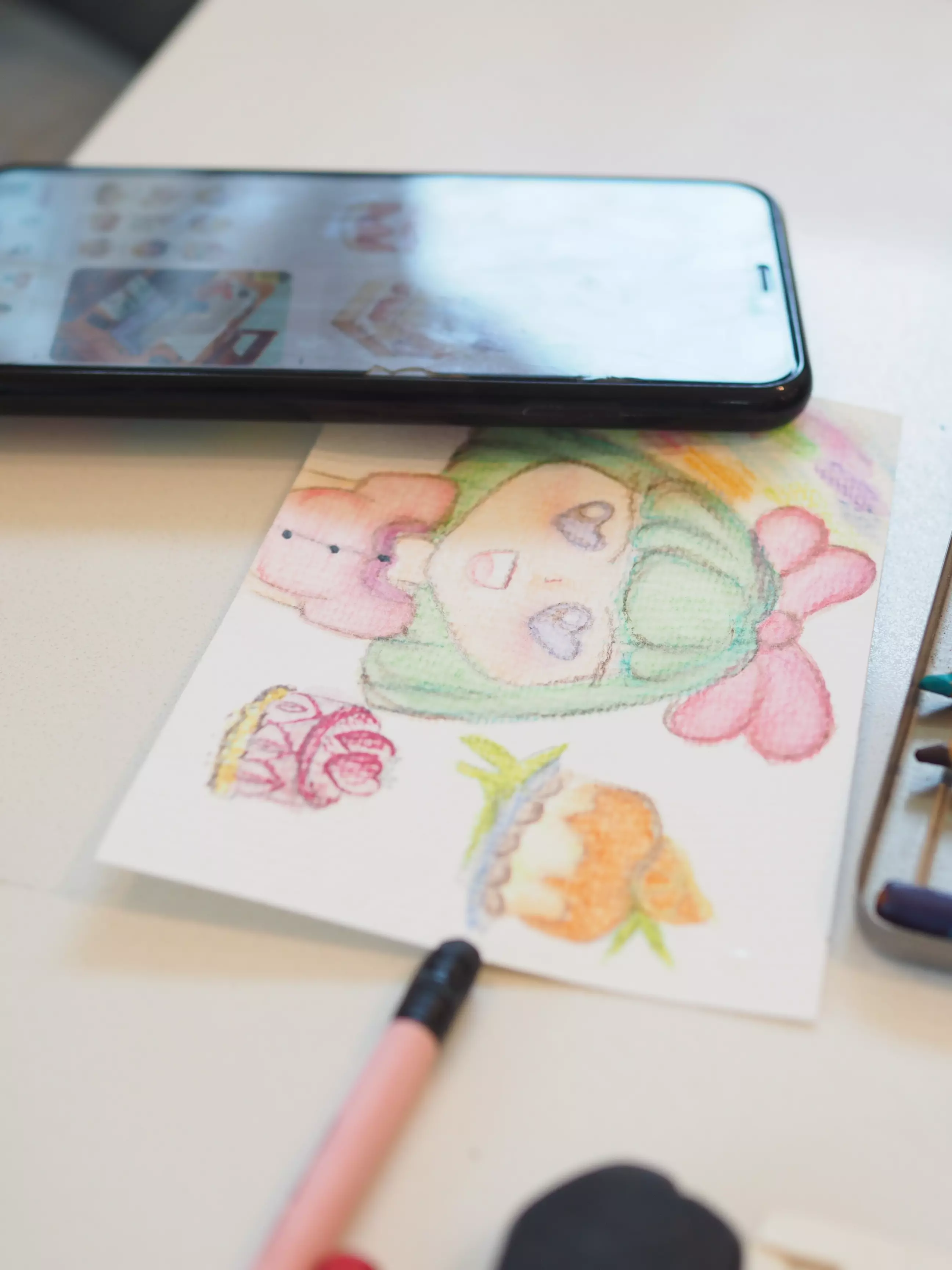 โปสการ์ดสีน้ำที่วาดเสร็จวางข้างโทรศัพท์