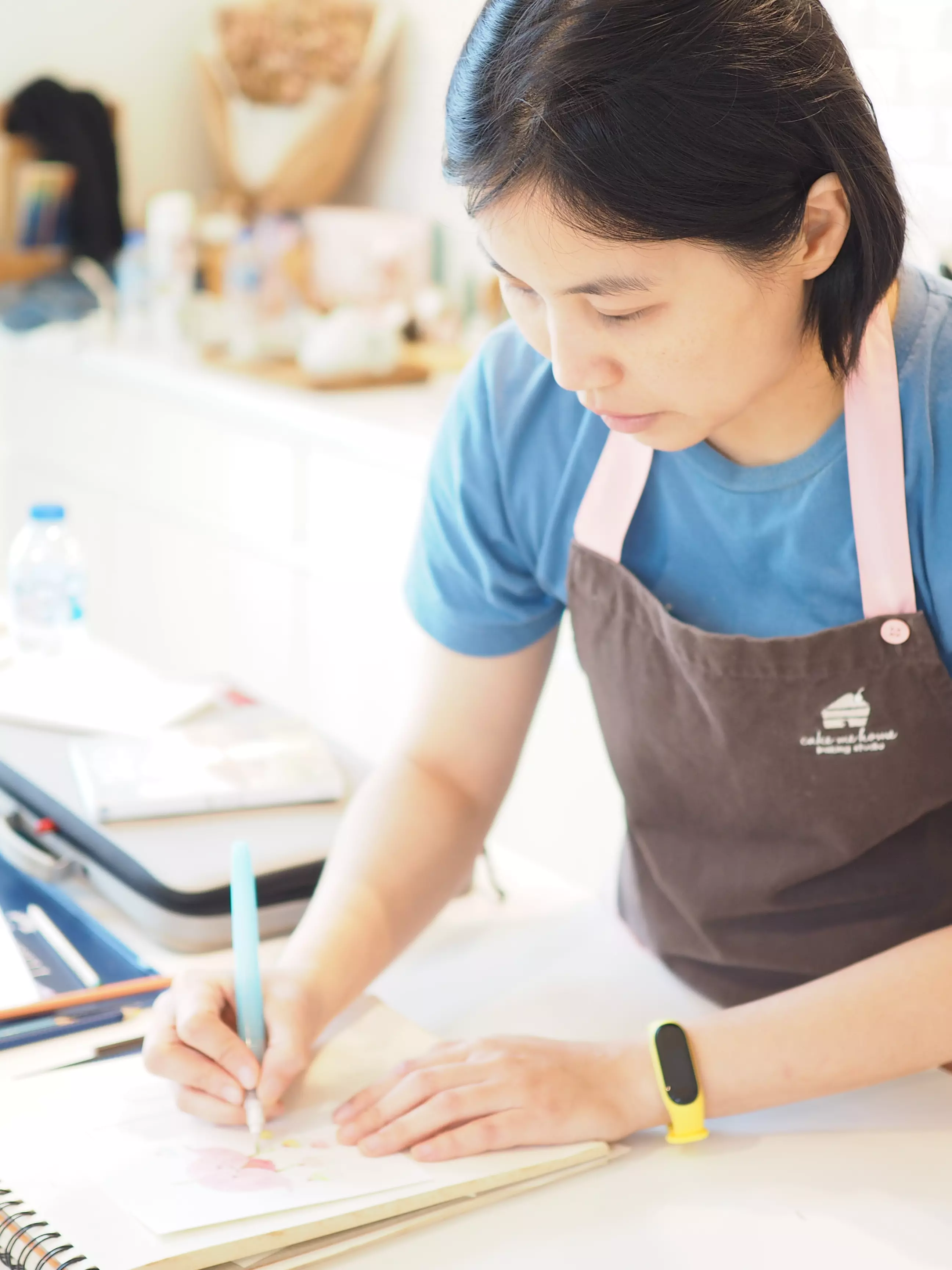 ผู้สอนในผ้ากันเปื้อน Cake Me Home กำลังลงสี