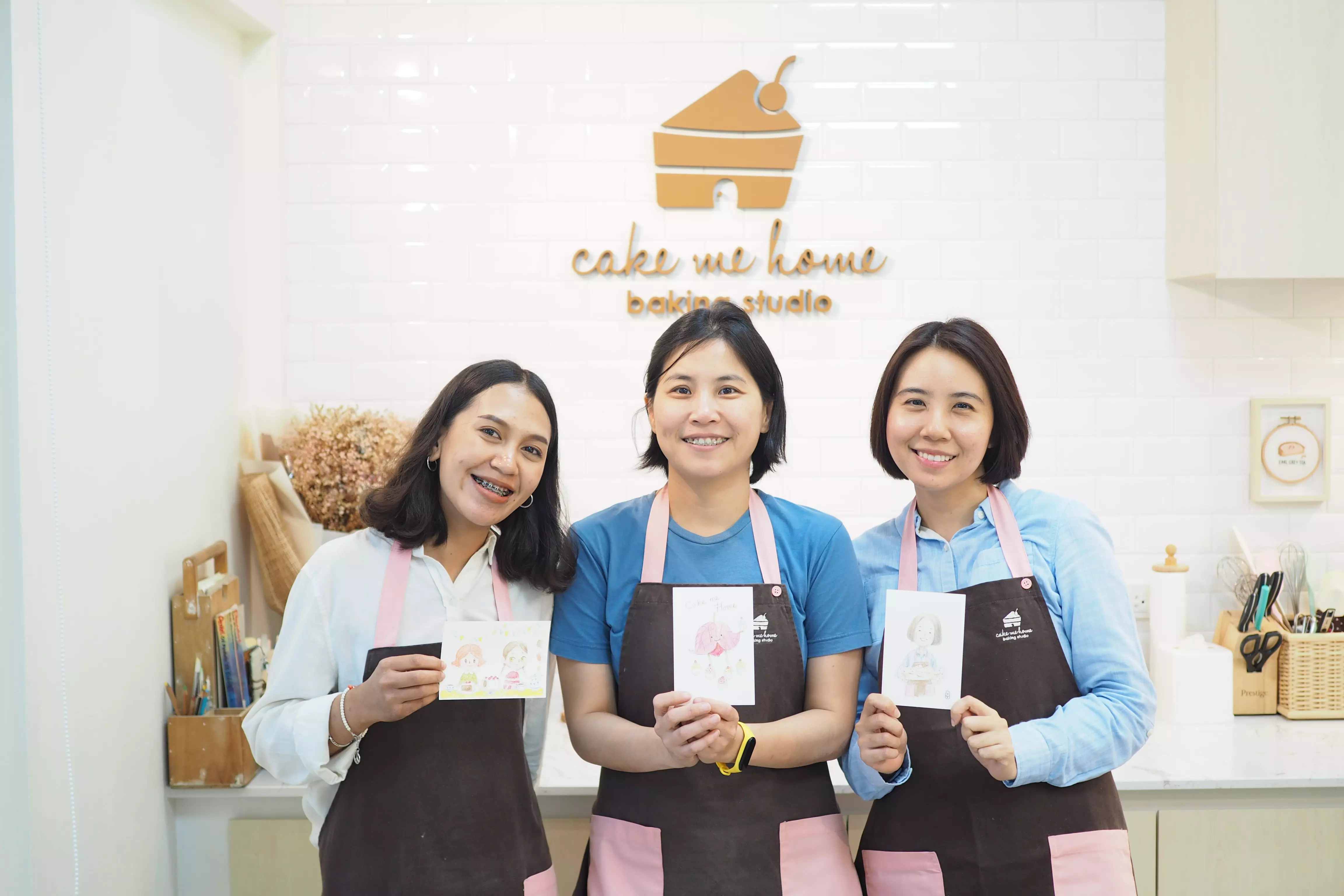 พิธีกรสามคนในผ้ากันเปื้อนถือโปสการ์ด